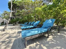 chaises longues ou chaises de plage sur la plage de sable blanc lors d'une chaude journée d'été dans un hôtel tropical de luxe photo