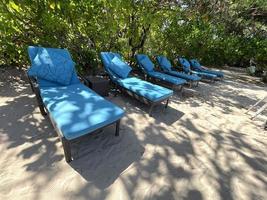 chaises longues ou chaises de plage sur la plage de sable blanc lors d'une chaude journée d'été dans un hôtel tropical de luxe photo