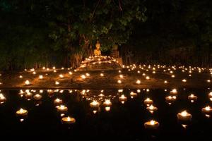 le jour spécial du bouddhisme, image de bouddha en position assise parmi les bougies photo