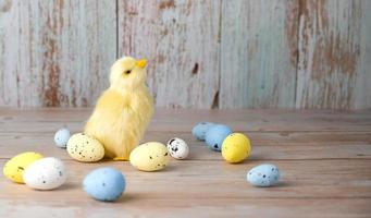 carte de voeux de pâques avec plave pour texte. petit poulet entouré d'oeufs colorés sur fond bleu photo