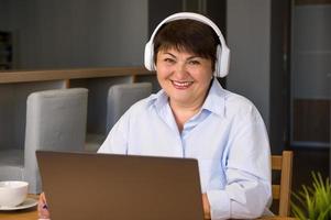 portrait en gros plan d'une femme aînée souriante et heureuse prenant note dans un cahier tout en écoutant un cours, un podcast ou tout simplement en communiquant avec quelqu'un. bannière copyspace photo