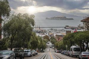 rue en pente avec voies de tramway menant vers la baie et ciel nuageux7 photo