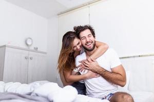 femme embrassant son partenaire au lit, couple heureux au lit montrant des émotions et de l'amour. beau couple d'amoureux s'embrassant au lit. beau jeune couple allongé ensemble sur le lit. photo