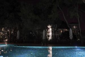 parasols et transats disposés au bord de la piscine illuminée la nuit en station photo