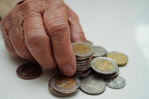 une femme âgée à la retraite comptant des pièces de monnaie et s'inquiète des dépenses mensuelles et du paiement des frais de traitement. photo