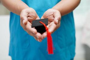 femme médecin asiatique tenant un chapeau de graduation à l'hôpital, concept d'éducation médicale. photo