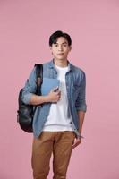 portrait d'un jeune étudiant souriant avec des livres et un sac à dos sur fond rose photo