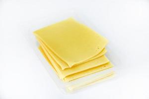 fines tranches de fromage sur un support en plastique. délicieux fromage jaune haché. fromage dans un emballage du magasin. photo