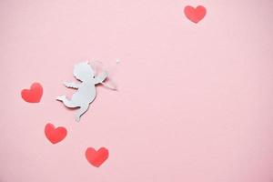 concept de la saint valentin. coeurs de couleur rouge et cupidon visant au coeur sur fond rose. cartes de Saint Valentin. photo