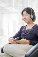 jeune femme asiatique cheveux courts écoutant de la musique dans le salon photo