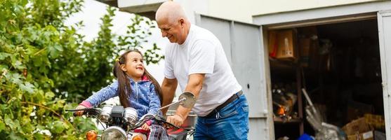 grand-père heureux et sa petite-fille près de vélo souriant photo