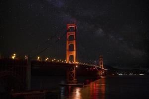 golden gate bridge illuminé sur la baie de san francisco avec champ d'étoiles dans le ciel photo