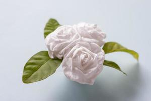 plier le bouquet de fleurs de jasmin par du papier toilette sur fond de papier bleu pour la fête des mères. photo