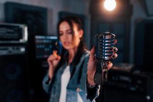 vue rapprochée du microphone. jeune belle interprète féminine répétant dans un studio d'enregistrement photo