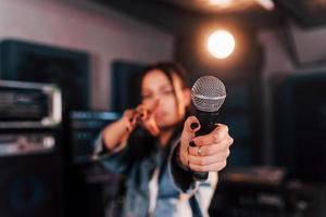 vue rapprochée du microphone. jeune belle interprète féminine répétant dans un studio d'enregistrement photo