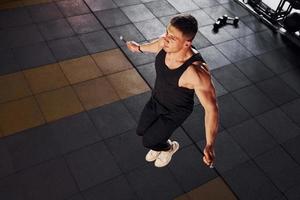 un homme fort en vêtements sportifs a une journée d'entraînement dans la salle de sport en utilisant une corde à sauter photo