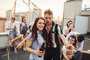 Couple heureux. un groupe de jeunes en vêtements décontractés fait la fête ensemble sur le toit pendant la journée photo