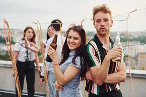 Couple heureux. un groupe de jeunes en vêtements décontractés fait la fête ensemble sur le toit pendant la journée photo