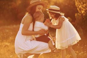 famille heureuse de mère, petit fils et fille passant du temps libre sur le terrain à l'heure ensoleillée de l'été photo