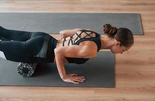 vue de côté. jeune femme en vêtements sportifs et au corps mince ont une journée de yoga fitness à l'intérieur photo