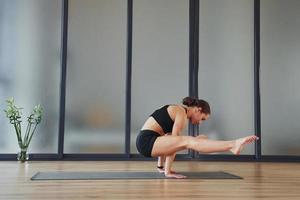 exercice difficile. jeune femme en vêtements sportifs et au corps mince ont une journée de yoga fitness à l'intérieur photo