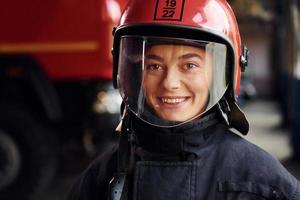 vue rapprochée. femme pompier en uniforme de protection debout près du camion photo