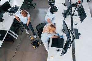 vue de dessus. un groupe de travailleurs nettoie un bureau moderne ensemble pendant la journée photo