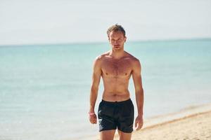 eau claire. jeune homme européen passe des vacances et profite de temps libre sur la plage de la mer photo