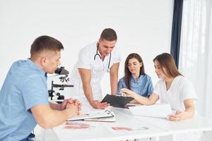 homme avec microscope. groupe de jeunes médecins travaille ensemble dans le bureau moderne photo