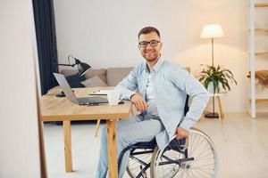 travailler sur un projet à domicile. homme handicapé en fauteuil roulant photo