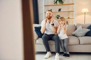 sur le canapé. s'amuser. père avec sa petite fille est à la maison ensemble photo