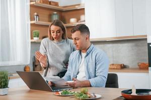 en utilisant Internet. couple préparant la nourriture à la maison dans la cuisine moderne photo