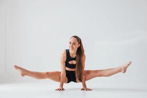 debout sur les mains. jeune femme en vêtements sportifs faisant de la gymnastique à l'intérieur photo