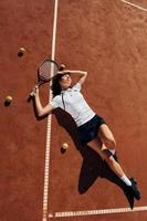 allongé sur le sol. La joueuse de tennis est sur le terrain pendant la journée photo