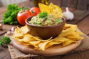 avocat guacamole, citron vert, tomate, oignon et coriandre, servi avec nachos - collation mexicaine traditionnelle photo