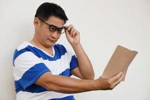 un homme d'âge moyen asiatique porte des lunettes lit un livre. concept, problème de vue. optométrie. verres à verres convexes ou concaves. myopie.maladie des yeux photo