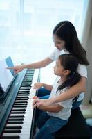 vacances en famille, autre aide sa fille à pratiquer ses cours de piano photo