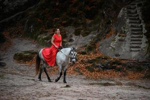 rochers dovbush et équitation, une femme à cheval dans une robe rouge pieds nus. photo