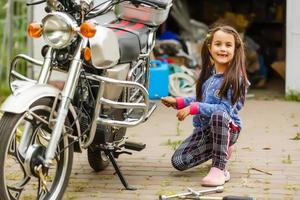 petite fille réparant une moto, étudiante en mécanique moto photo