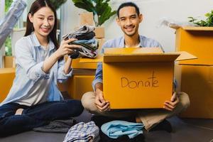 homme et femme bénévoles asiatiques emballant une boîte en tissu et faisant un don à d'autres personnes et partageant à une association caritative photo