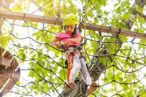 fille grimpant dans un parcours de corde en hauteur profitant de l'aventure photo