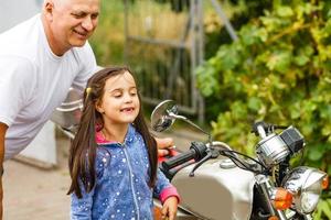 grand-père heureux et sa petite-fille près de vélo souriant photo