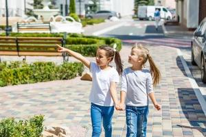 deux belles petites filles sur une balançoire en plein air dans l'aire de jeux en été photo