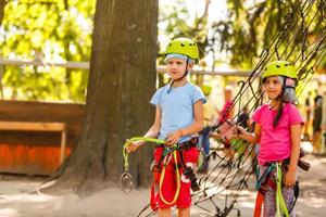 petits enfants heureux dans un parc à cordes sur fond de bois photo