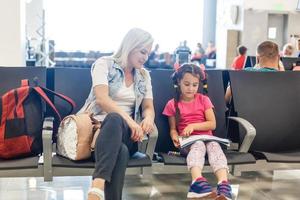 maman et enfant attendent leur avion à l'aéroport. les passagers attendent leur transport en gare photo