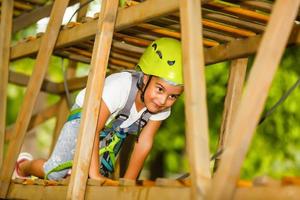 petite fille heureuse dans un parc à cordes sur le fond du bois photo