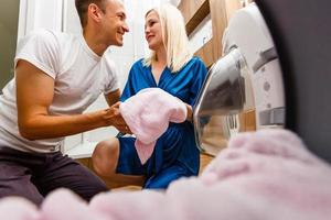 couple drôle chargeant des vêtements dans une machine à laver