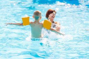 belle jeune mère avec petit fils et fille dans la piscine. photo