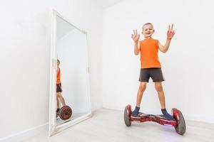 Heureux petit garçon sur un gyroboard sur fond blanc photo