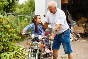 grand-père heureux et sa petite-fille près de vélo souriant photo